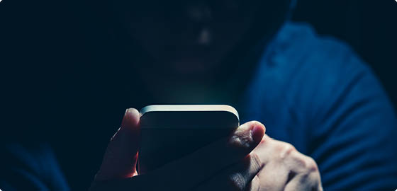 Hooded cyber crime hacker using mobile phone internet hacking in to cyberspace,online personal data security concept 