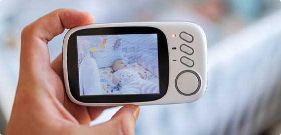 Close up of hand holding baby now modern baby monitor and recording baby in crib 