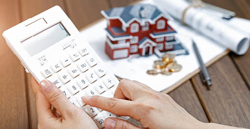 A female hand operating a calculator in front of a Villa house model