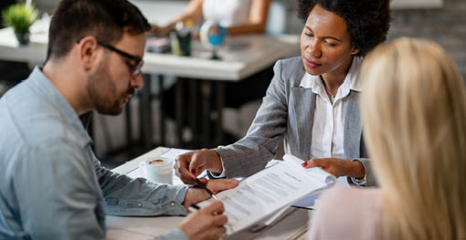 Black female real estate agent showing to a couple where to sign the contract during the meeting in the office 